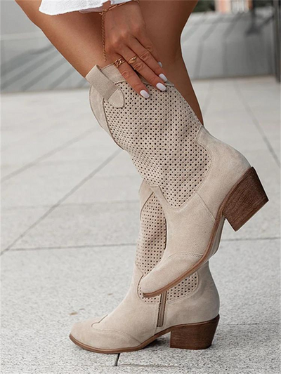 Beige cream boots with geometric laser perforation design panels and natural wood block heel, on-model close-up showing textured upper construction and western-style shaft