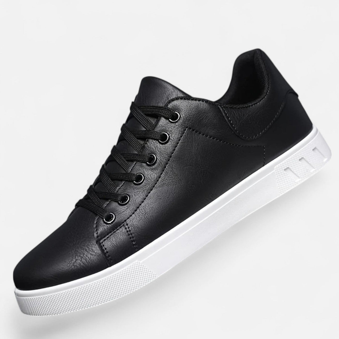 Black leather low-top sneaker with round toe and six-eyelet lace-up closure, elevated angle showing off-white platform rubber sole and padded collar construction