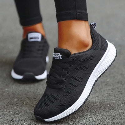 Black mesh running trainers with contrast white midsole and grey collar trim, on-model worn view displaying engineered knit upper and grooved rubber outsole