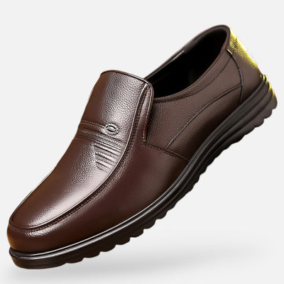 Brown grain leather casual slip-on with textured vamp panel and contrast stitching, perspective view displaying deep tread rubber sole and yellow accent heel pull