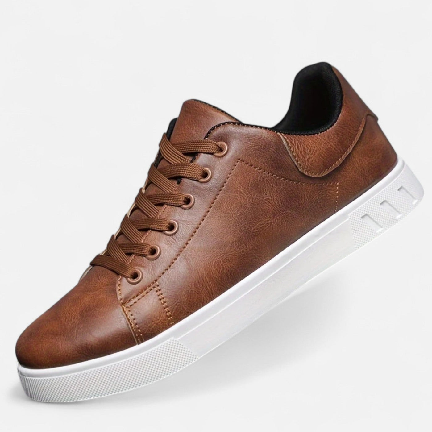 Brown leather casual sneaker with tonal flat laces and black collar lining, angled view displaying white textured rubber cupsole and contrast stitching detail
