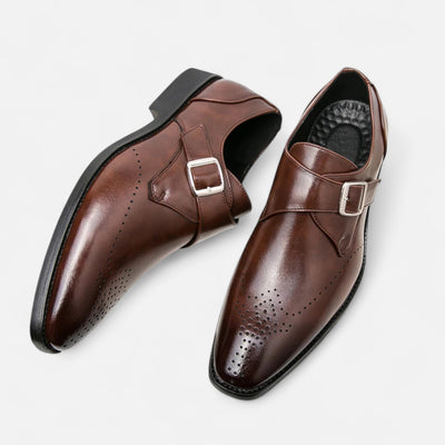 Brown leather monk strap formal shoes with metal buckle fastening and decorative brogue perforations, overhead paired display featuring elongated toe shape and blake stitch sole