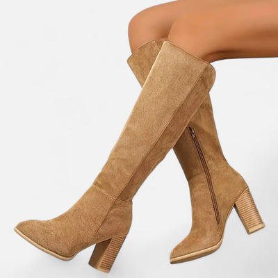 Camel beige suede tall boots with chunky grooved block heel and pointed toe, on-model side angle showing knee-length shaft and interior side zipper detail