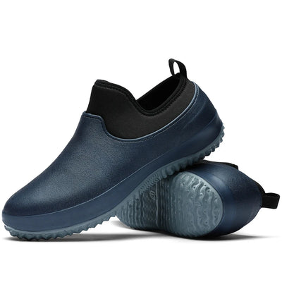 Navy blue slip-on clogs with black neoprene collar and tonal blue rubber outsole, paired view displaying molded upper construction and wave pattern traction sole