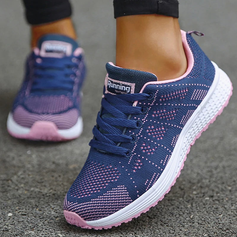 Navy blue and pink mesh athletic shoes with gradient knit pattern and pink accent collar, on-model perspective showing textured mesh zones and white cushioned midsole