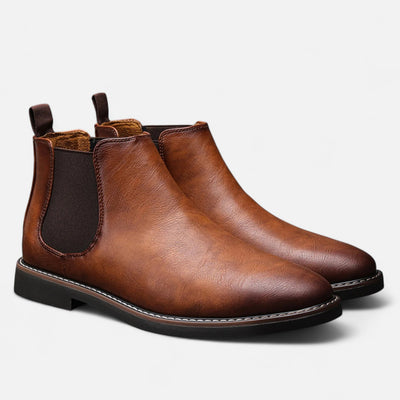 Tan cognac leather Chelsea boots with black elastic side gussets and pull tabs, paired three-quarter view showing contrast welt stitching and textured rubber sole